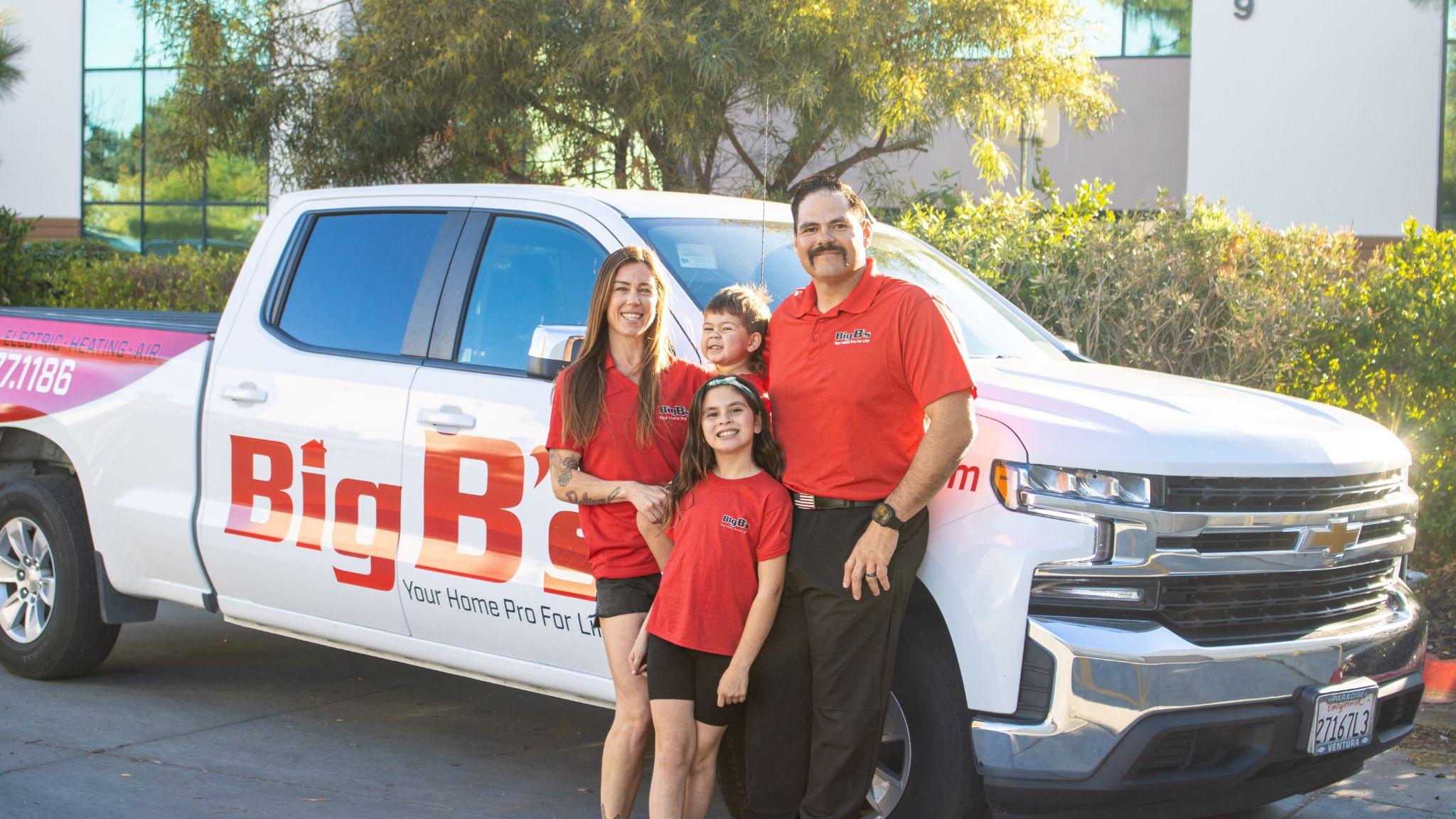 Big B's family smiling in front of Big B's company truck 